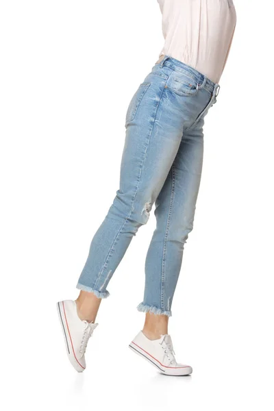 Mooie vrouwelijke benen in blauwe jeans en sportschoenen geïsoleerd op witte achtergrond — Stockfoto