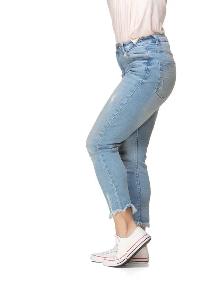 Pernas femininas finas em jeans azuis e sapatos esportivos isolados no fundo branco — Fotografia de Stock