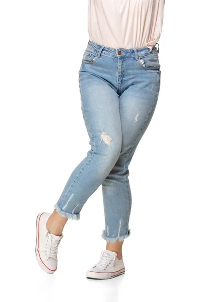 Slim female legs in blue jeans and sport shoes isolated on white background — Stock Photo, Image