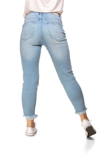 Vue arrière des jambes féminines en jeans et chaussures de sport isolées sur fond blanc — Photo