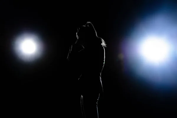 Silhouette of sad woman posing isolated on dark background.