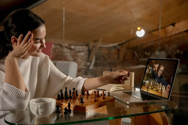 Два человека красивая девушка и маленький мальчик играют в шахматы онлайн с помощью ноутбука. — стоковое фото