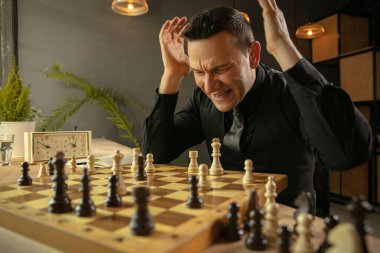 Genç beyaz satranç oyuncusu evde oturuyor ve satranç oynuyor..