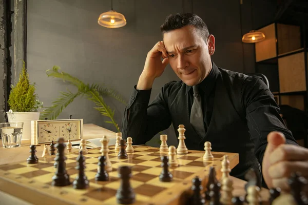 Серьезный шахматист сидит дома и играет в шахматы в одиночку. — стоковое фото