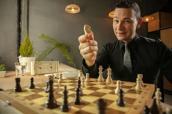 Young Caucasian man chess player sitting at home and playing chess.