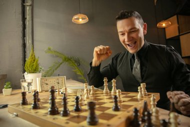 Mutlu beyaz erkek satranç oyuncusu evde oturup satranç oynuyor..