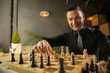 Mutlu beyaz erkek satranç oyuncusu evde oturup satranç oynuyor..