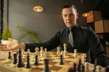 Genç beyaz satranç oyuncusu evde oturuyor ve satranç oynuyor..
