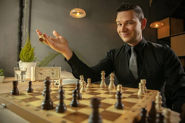 Happy Caucasian man chess player sitting at home and playing chess.