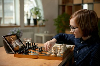 Küçük beyaz satranç oyuncusu bilgisayarı kullanarak online satranç oynuyor..