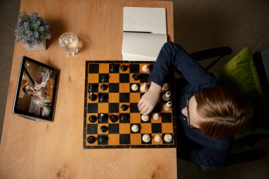 Küçük beyaz satranç oyuncusu bilgisayarı kullanarak online satranç oynuyor..