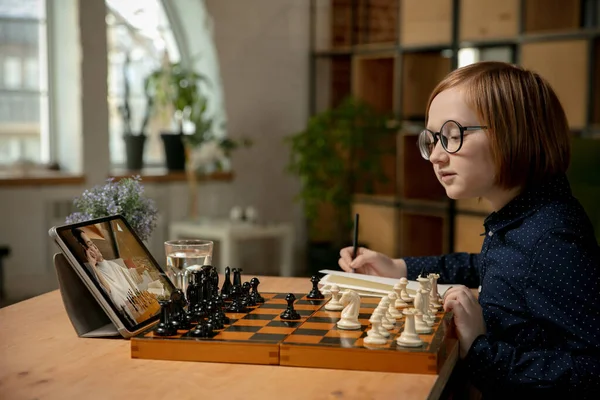 Little Caucasian boy chess player playing chess online using laptop.