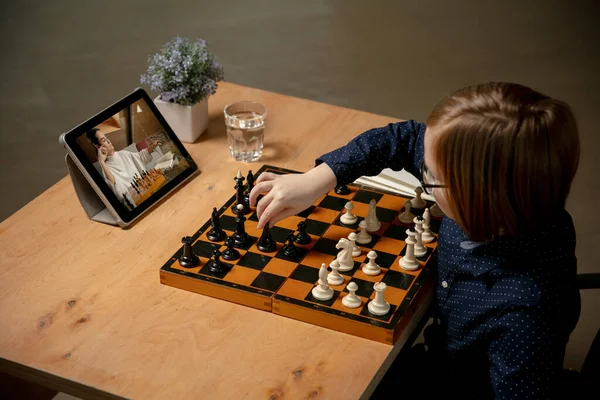 Маленький белый мальчик и его тренер, друг играет в шахматы онлайн с помощью ноутбука. — стоковое фото