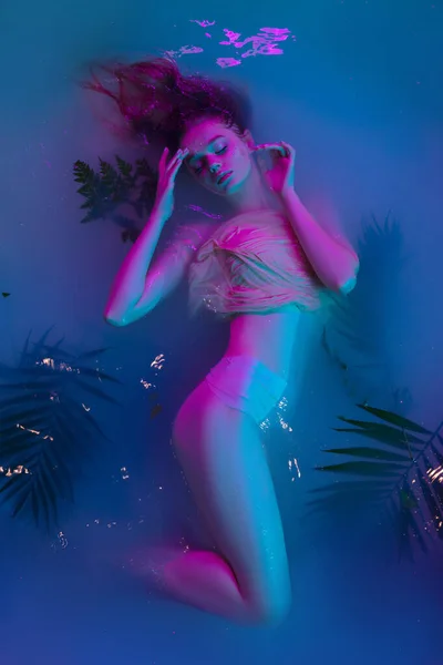Modern neon ışıkta suda poz veren güzel bir kızın portresi.. — Stok fotoğraf