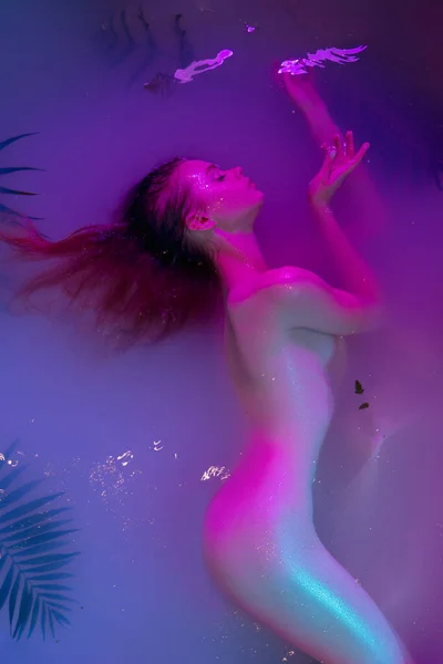 Közelkép fiatal gyönyörű lány pózol a víz kék neon fény. — Stock Fotó