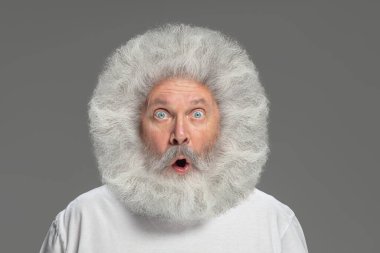 Gri arkaplanda izole edilmiş yaşlı, gri saçlı bir adamın yakın plan portresi..