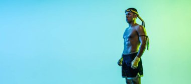 Genç Taylandlı boksör mavi arka planda neon ışıkta poz veriyor..