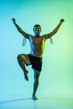 Genç Taylandlı boksör mavi arka planda neon ışıkta poz veriyor..