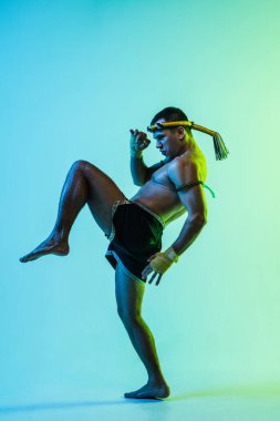 Genç adam Thai boksör eğitimi mavi arka planda neon ışığı altında.