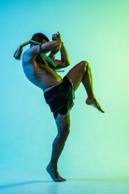 Genç adam Thai boksör eğitimi mavi arka planda neon ışığı altında.