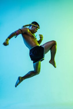 Genç adam Thai boksör eğitimi mavi arka planda neon ışığı altında.