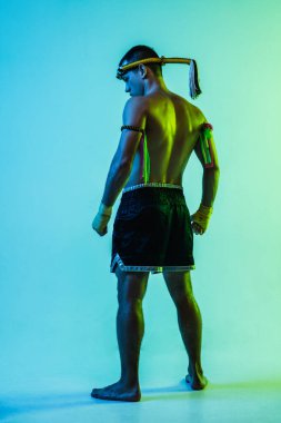 Genç Taylandlı boksör mavi arka planda neon ışıkta poz veriyor..