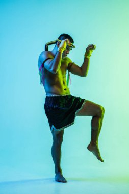 Genç adam Thai boksör eğitimi mavi arka planda neon ışığı altında.