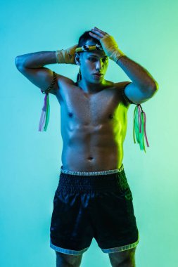 Genç adam Thai boksör eğitimi mavi arka planda neon ışığı altında.