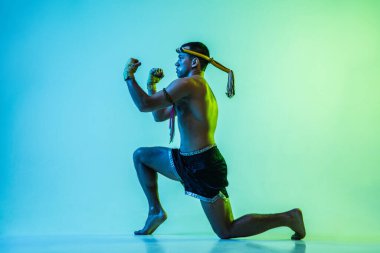 Genç adam Thai boksör eğitimi mavi arka planda neon ışığı altında.