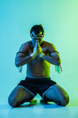 Tayland boksu yapan bir adam mavi arka planda neon ışığında.