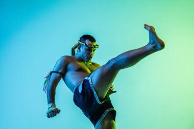 Genç adam Thai boksör eğitimi mavi arka planda neon ışığı altında.