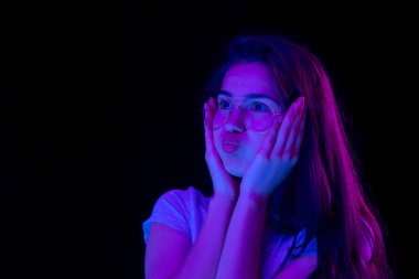 Güzel bir kızın yakın plan portresi. Karanlık arka planda, neon ışıklı..