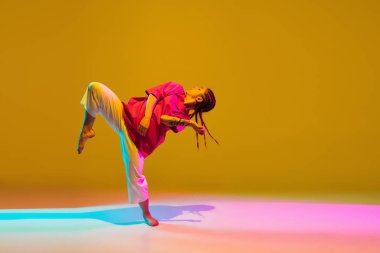 Neon ışıklarıyla renkli arka planda hip-hop dansı yapan sportif kız.