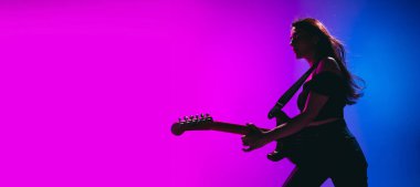 Genç bayan gitaristin silueti neon arka planda izole edilmiş..