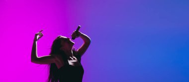 Mavi-pembe arka planda izole edilmiş genç bayan şarkıcının portresi.