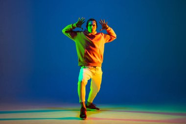 Dans eden genç erkek dansçı hip-hop mavi arka planda izole edilmiş neon ışıkta