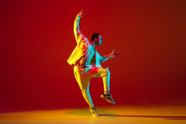 Dans eden genç erkek dansçı hip-hop kırmızı arka planda izole edilmiş neon ışıkta