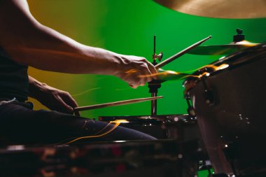 Neon renginde yeşil-kırmızı arkaplanda izole edilmiş davul çalan erkek ellerinin yakın çekimi