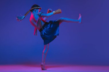 Genç Taylandlı boksör mavi arka planda neon ışıkta eğitim görüyor..