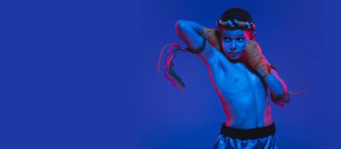 Genç Taylandlı boksör mavi arka planda neon ışıkta poz veriyor..