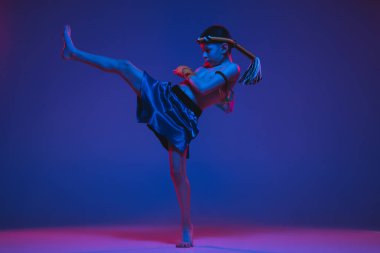 Genç Taylandlı boksör mavi arka planda neon ışıkta eğitim görüyor..