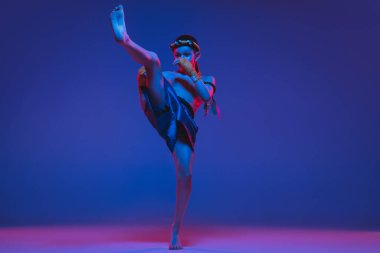 Genç Taylandlı boksör mavi arka planda neon ışıkta eğitim görüyor..