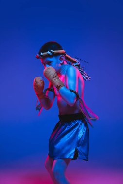 Genç Taylandlı boksör mavi arka planda neon ışıkta eğitim görüyor..