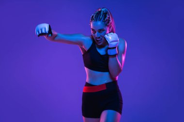 Atletik bayan MMA dövüşçüsü mavi-pembe arka planda neon ışıkta izole edildi.