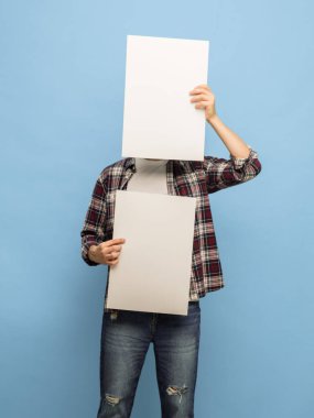 Mavi arka planda boş kağıt yaprakları olan genç bir adamın portresi.