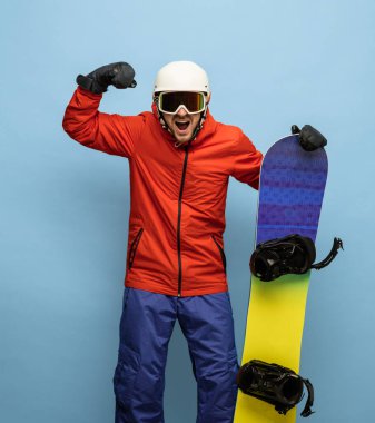 Mavi arka planda izole edilmiş kar kayağı takımlı erkek snowboardcu..