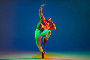 Dans eden genç erkek dansçı hip-hop mavi arka planda izole edilmiş neon ışıkta