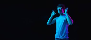 Genç adamın portresi koyu renkli arka planda neon ışıkta izole edilmiş.