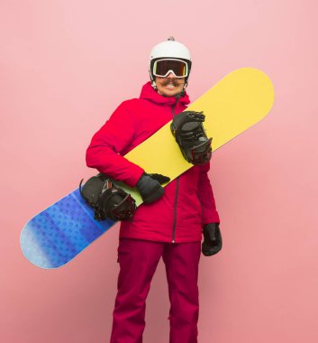 Pembe arka planda izole edilmiş parlak kayak takımlı kayak takımlı erkek snowboardcu.