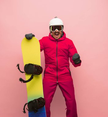 Pembe arka planda izole edilmiş parlak kayak takımlı kayak takımlı erkek snowboardcu.